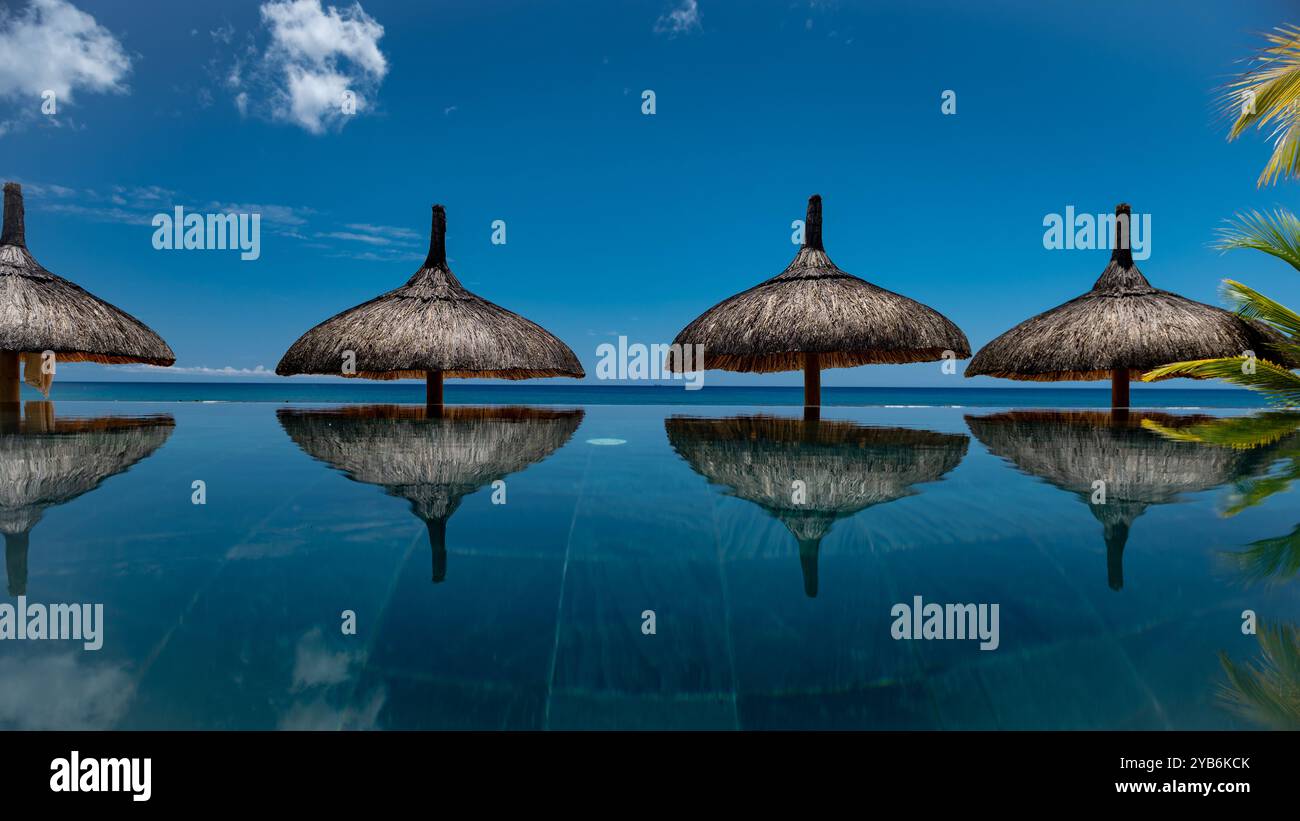 Parasols reflétant sur la piscine en face de l'océan Banque D'Images