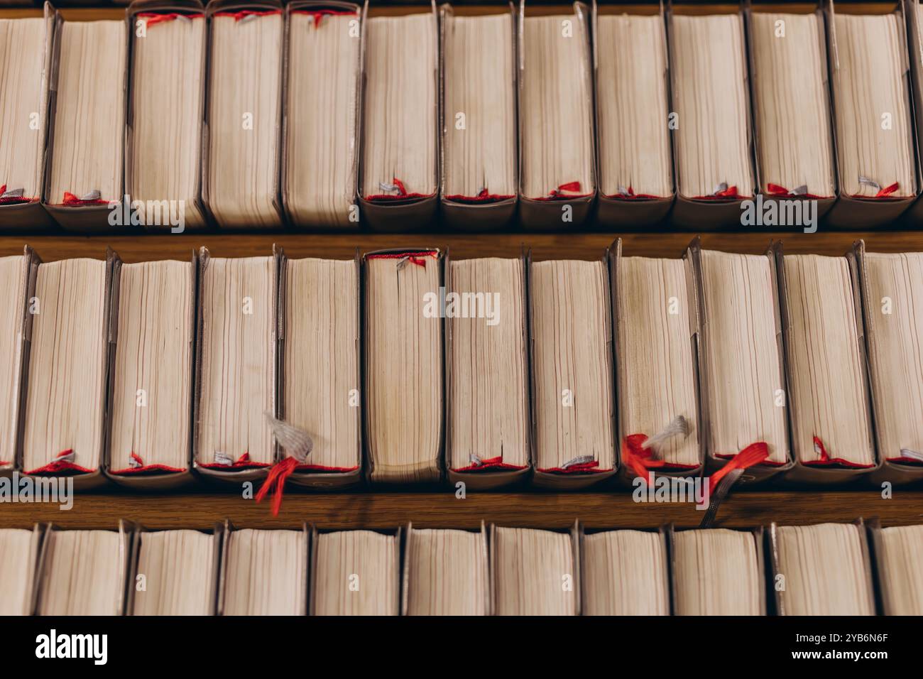 Vue de haut en bas des rangées de vieux livres avec des pages usées et des signets rouges, soigneusement disposés sur des étagères en bois. Photo de haute qualité Banque D'Images