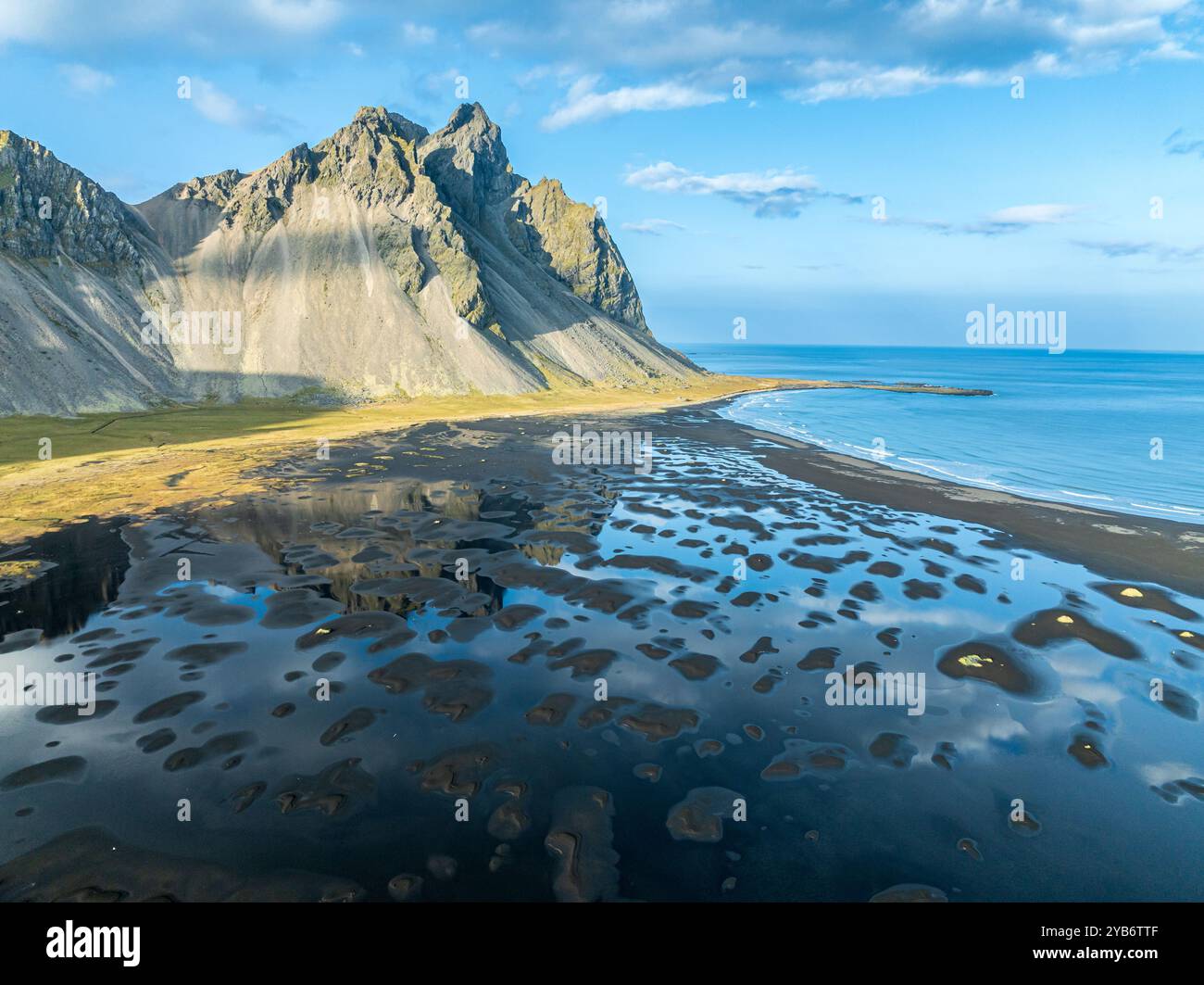 Vue aérienne de Mt. Vestrahorn , plage de lave noire, reflets sur l'eau, Stokksnes, à l'est de Höfn, Fjords de l'est, Islande Banque D'Images