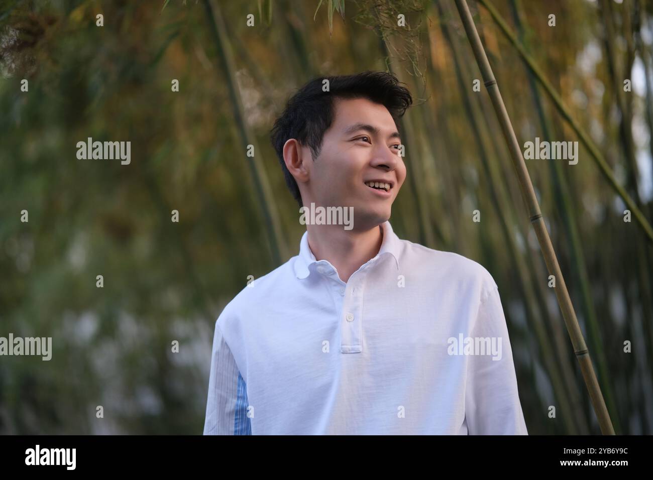 Vue latérale du sourire beau jeune homme asiatique, à la forêt de bambous Banque D'Images