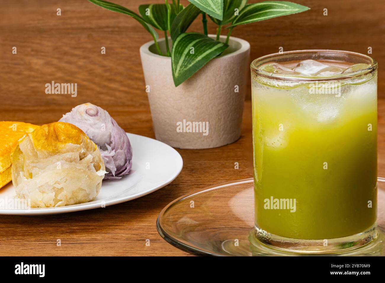 Gros plan sur le jus de goyave vert froid avec glaçon en verre transparent sur soucoupe en verre avec gâteau de lune chinois multicolore et cak en couches Banque D'Images