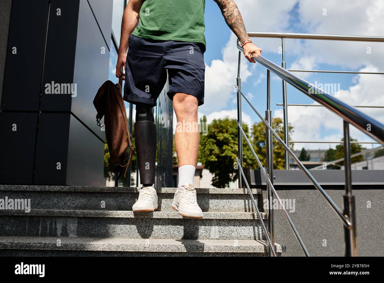 Un jeune homme avec une jambe prothétique descend en toute confiance les escaliers extérieurs, embrassant la diversité. Banque D'Images Un jeune homme avec une jambe prothétique descend en toute confiance les escaliers extérieurs, embrassant la diversité. Banque D'Images