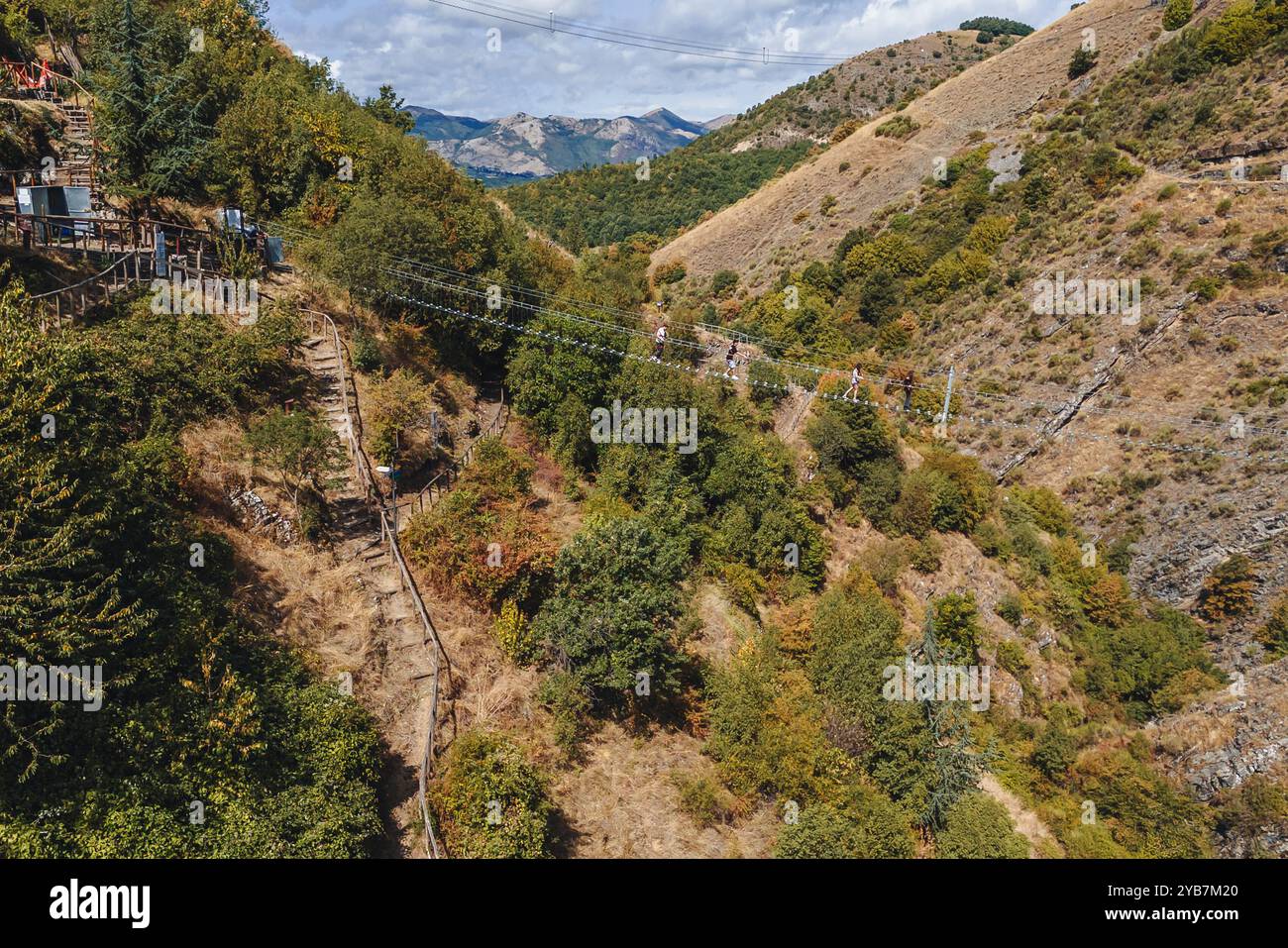 Sasso di Castalda, Italie - août 2024 : une vue aérienne capture une longue passerelle suspendue s'étendant sur un terrain rocheux avec un vert environnant A. Banque D'Images