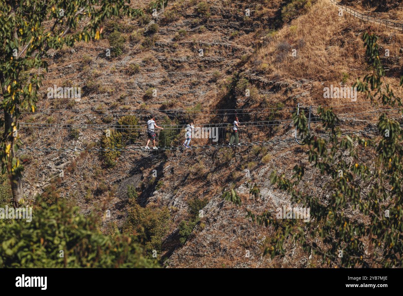 Sasso di Castalda, Italie - août 2024 : une vue aérienne capture une longue passerelle suspendue s'étendant sur un terrain rocheux avec un vert environnant A. Banque D'Images