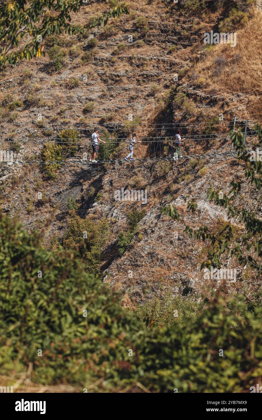 Sasso di Castalda, Italie - août 2024 : une vue aérienne capture une longue passerelle suspendue s'étendant sur un terrain rocheux avec un vert environnant A. Banque D'Images