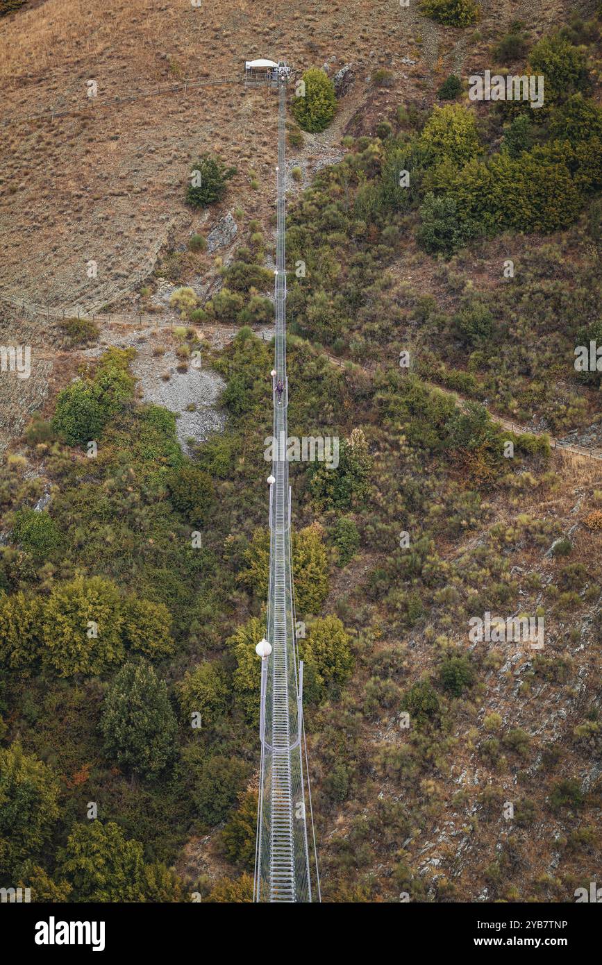 Sasso di Castalda, Italie - août 2024 : une vue aérienne capture une longue passerelle suspendue s'étendant sur un terrain rocheux avec un vert environnant A. Banque D'Images