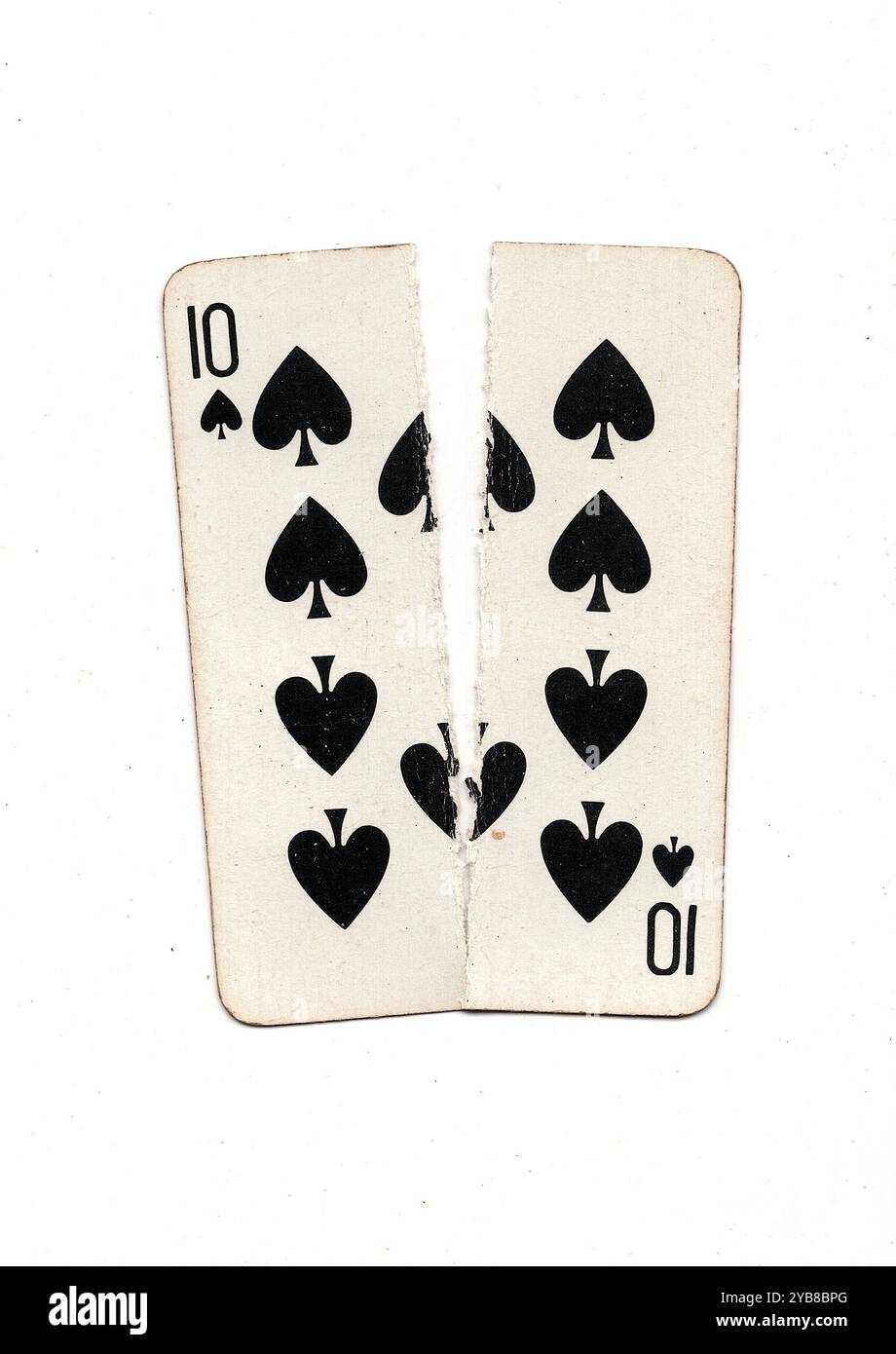 Une carte à jouer vintage déchirée en deux de haut en bas sur un fond blanc. Banque D'Images