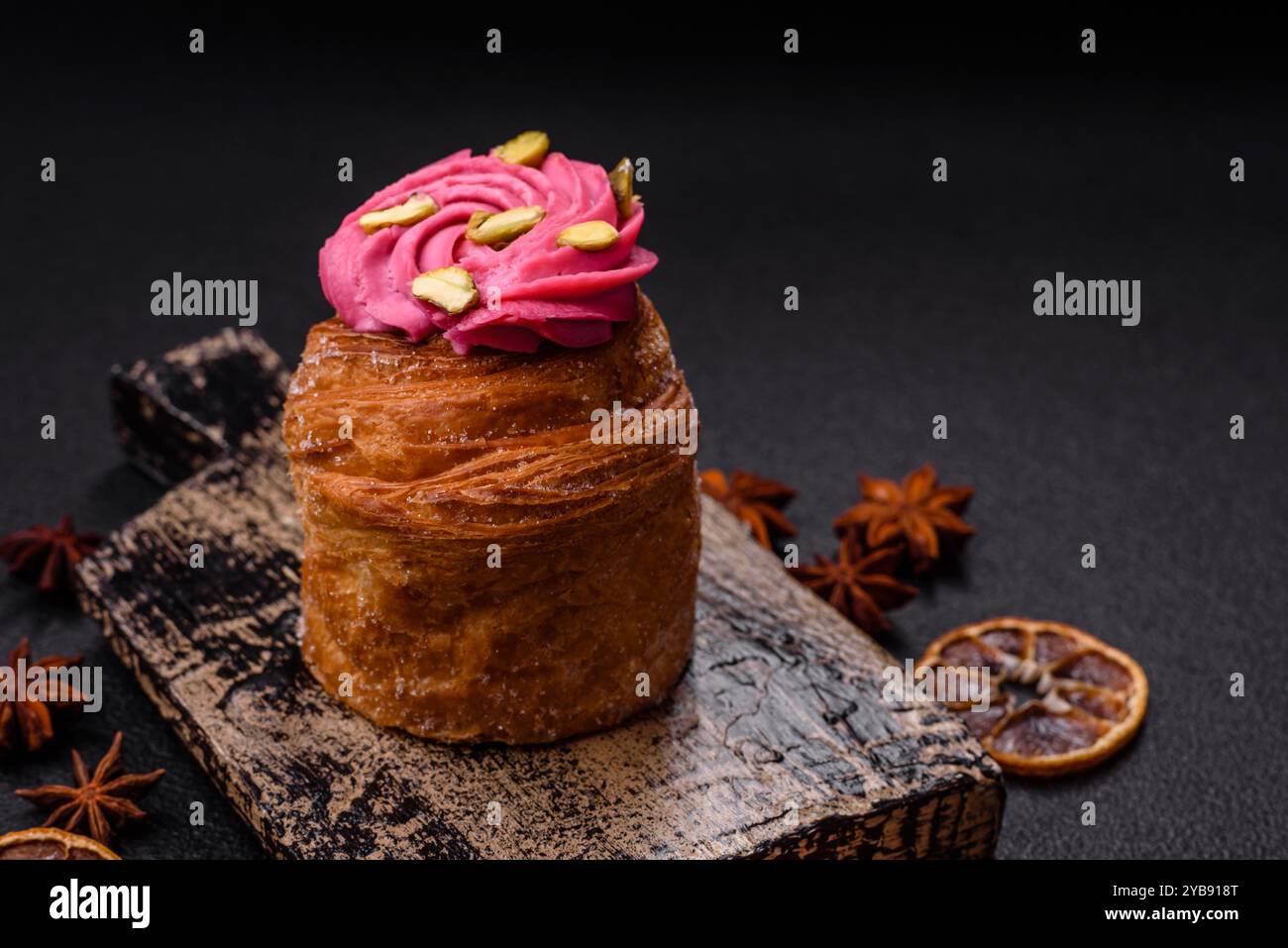 Craffin sucré ou panettone garni de crème aromatisée à la framboise et à la pistache sur un fond de béton foncé Banque D'Images