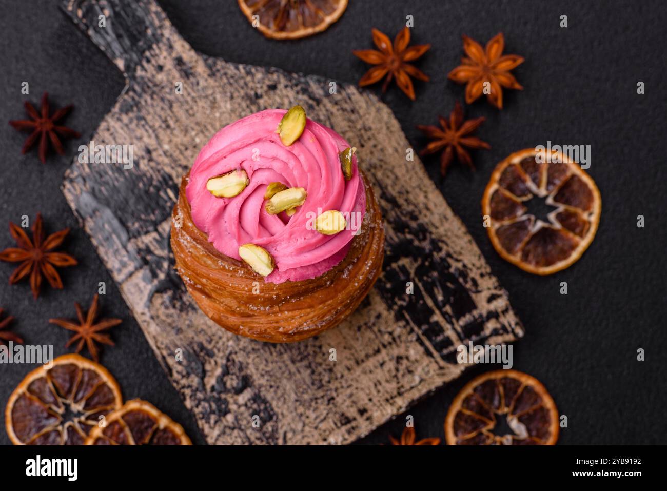 Craffin sucré ou panettone garni de crème aromatisée à la framboise et à la pistache sur un fond de béton foncé Banque D'Images