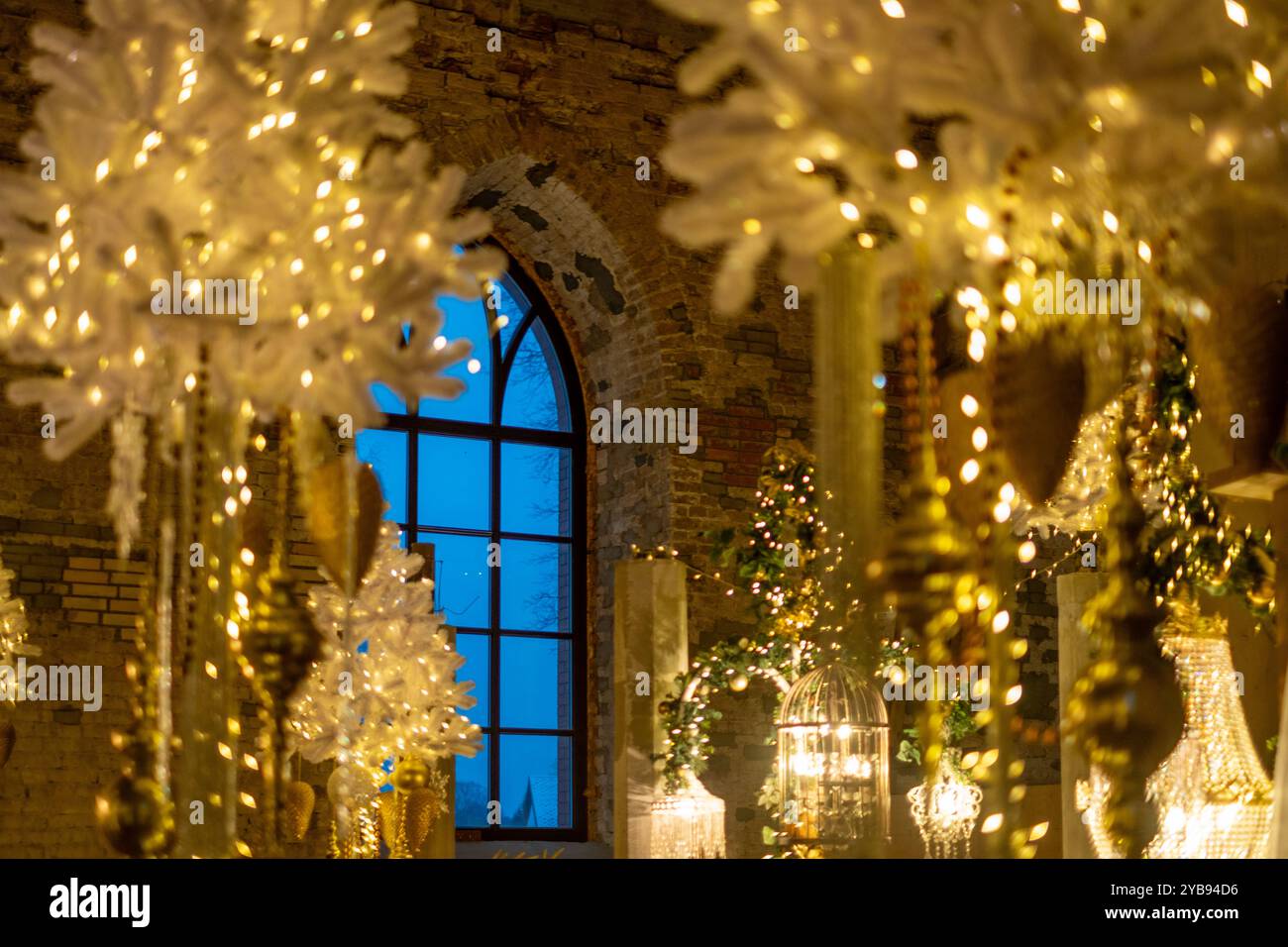 Ce cadre intérieur enchanteur présente d'élégantes décorations de Noël blanches et dorées, des lumières scintillantes et une atmosphère hivernale chaleureuse à travers une fenêtre Banque D'Images