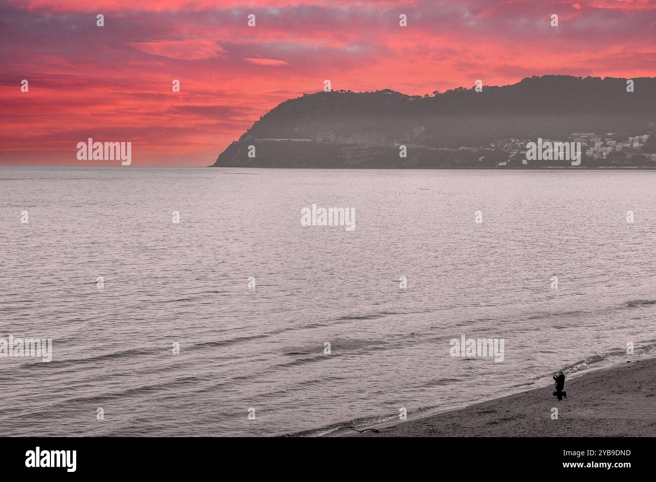 Noir et blanc avec couleur sélective. Vue surélevée sur la plage avec le promontoire de Capo Mele et un ciel de coucher de soleil spectaculaire au printemps, Alassio, Ligurie, Italie Banque D'Images