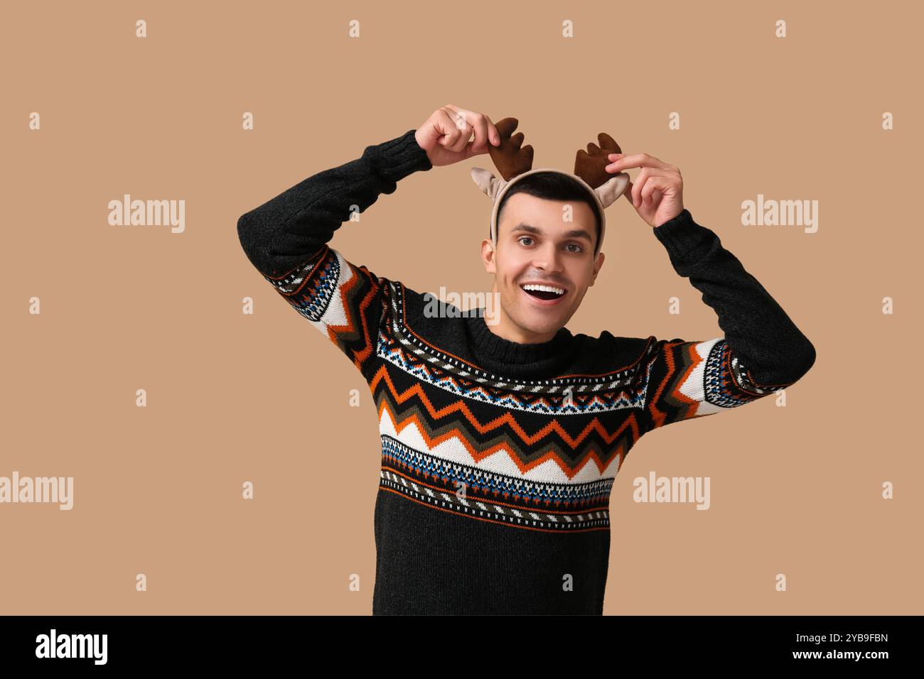 Heureux jeune homme dans des cornes de renne sur fond beige Banque D'Images