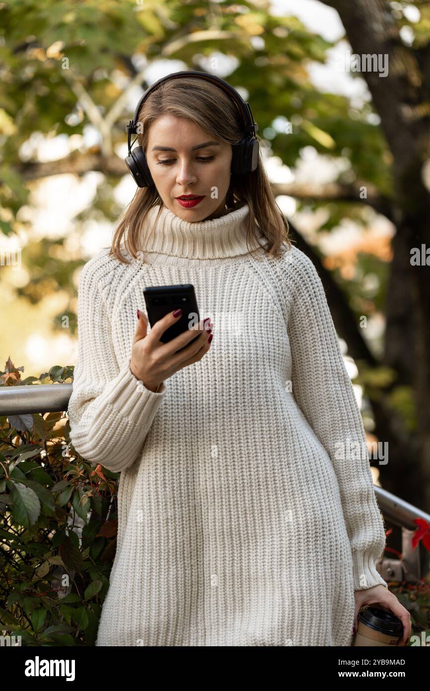 fille écoutant de la musique sur des écouteurs sans fil à l'extérieur en automne, style de vie urbain Banque D'Images