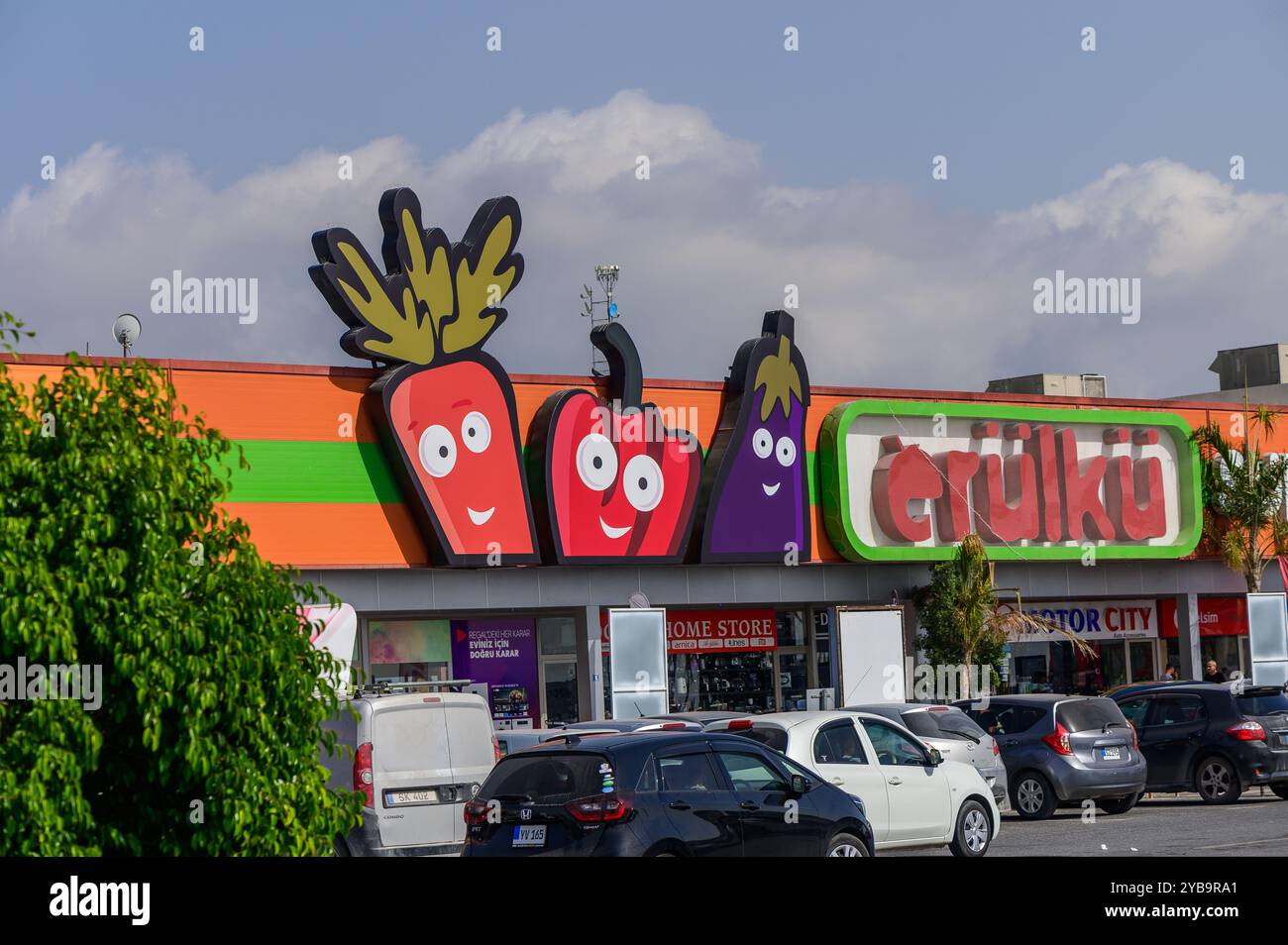 Une épicerie dynamique affiche de grands personnages végétaux de dessins animés sur sa façade, attirant les acheteurs dans une zone commerciale animée sous un bleu clair Banque D'Images