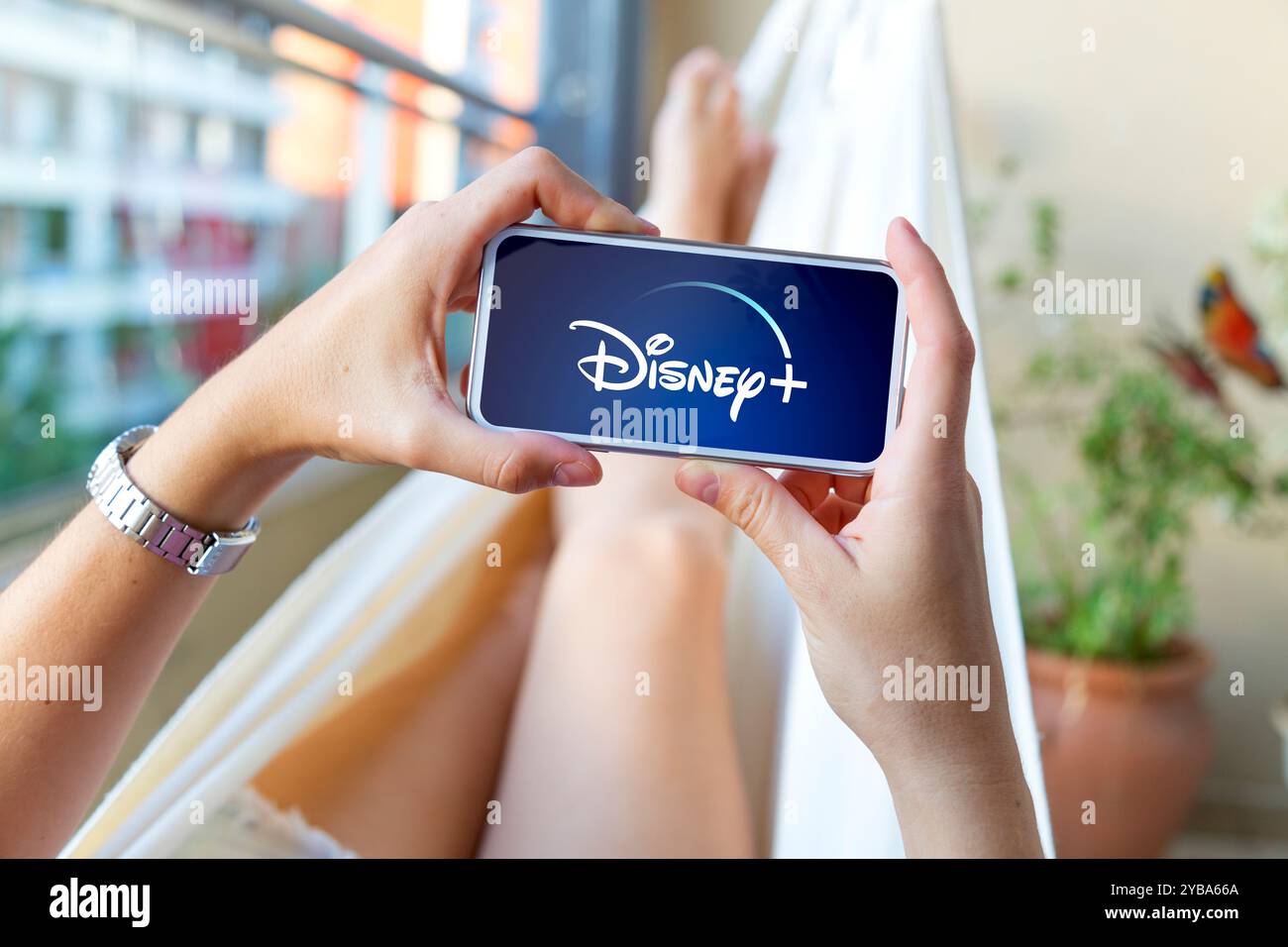 Jeune femme utilisant un téléphone portable avec Disney plus logotype à l'écran. Vidéo en streaming et application de divertissement. Rosario, Argentine - 16 octobre 2024 Banque D'Images