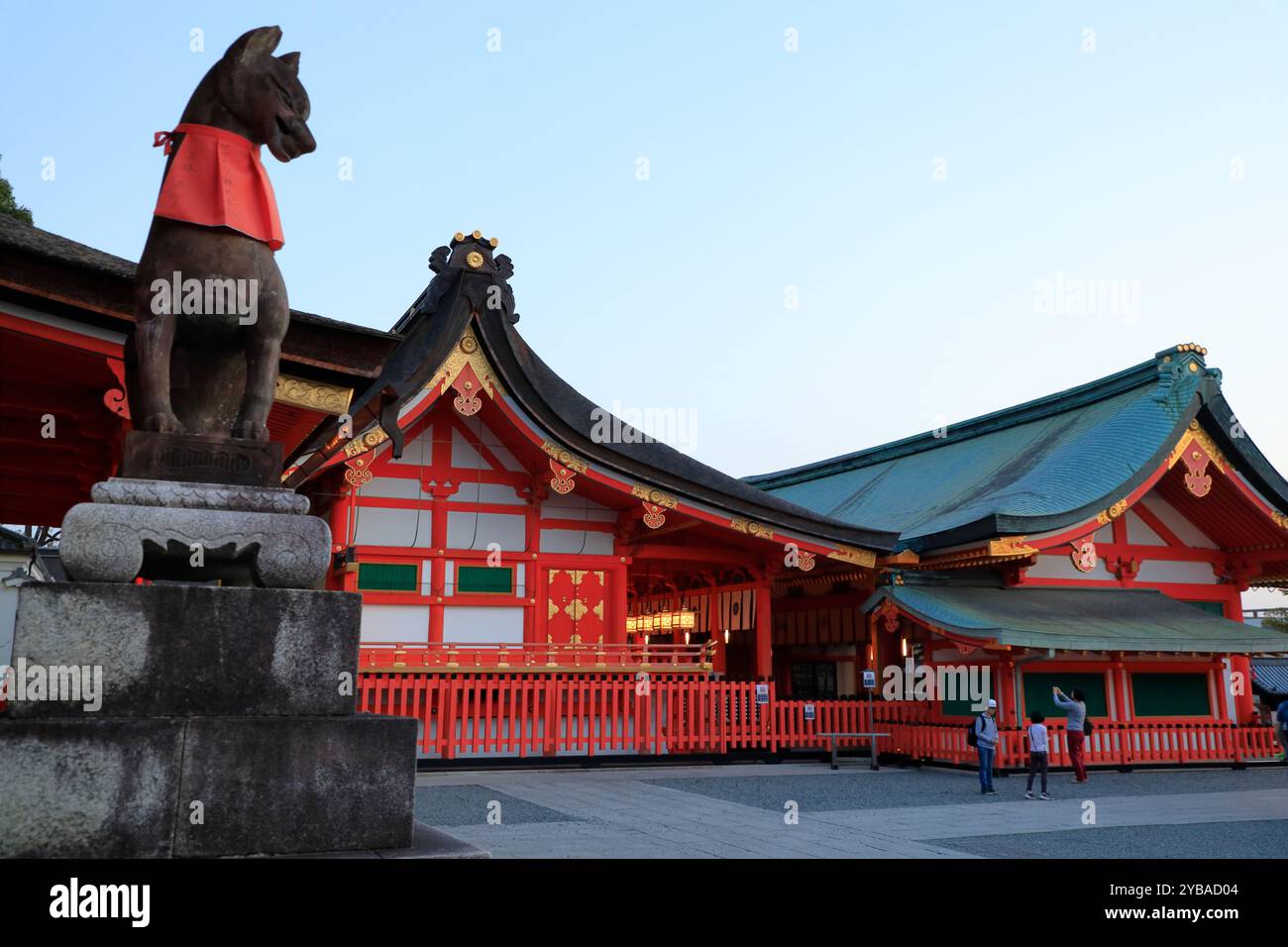 Sanctuaire Fushimi Inari-taisha avec une statue de kitsune (esprit renard) au premier plan en début de soirée.Kyoto.Japan Banque D'Images