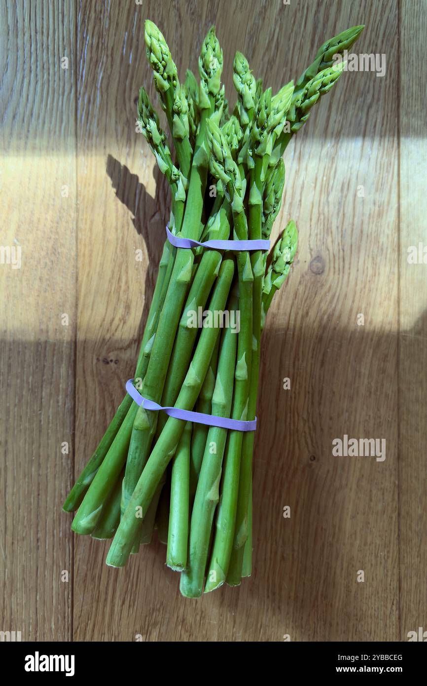 Vue de nature morte d'au-dessus du bouquet d'asperges vertes vibrantes sur fond en bois Banque D'Images