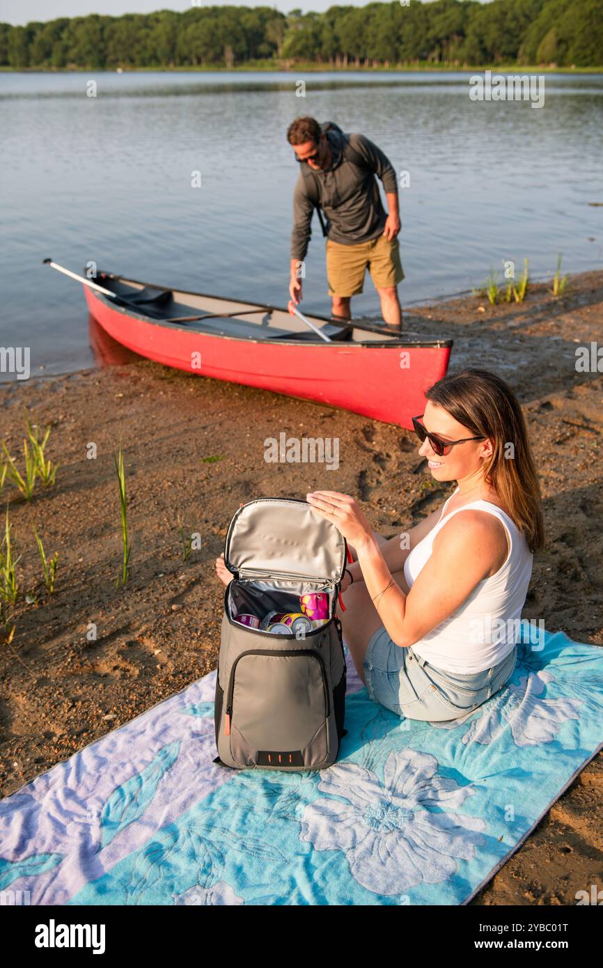 Couple avec des sacs à dos ayant pique-nique en canoë le jour d'été Banque D'Images