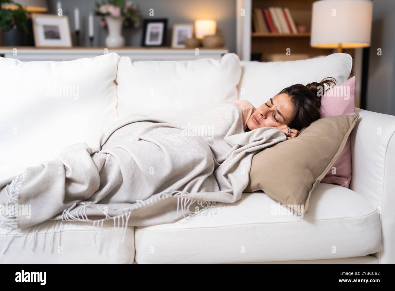 Femme dormant sur le canapé à la maison se reposant enveloppant dans le plaid ressentant de mauvais symptômes. Fille souffrant de grippe saisonnière ou de rhume. Se sentir malsain avec influenz Banque D'Images