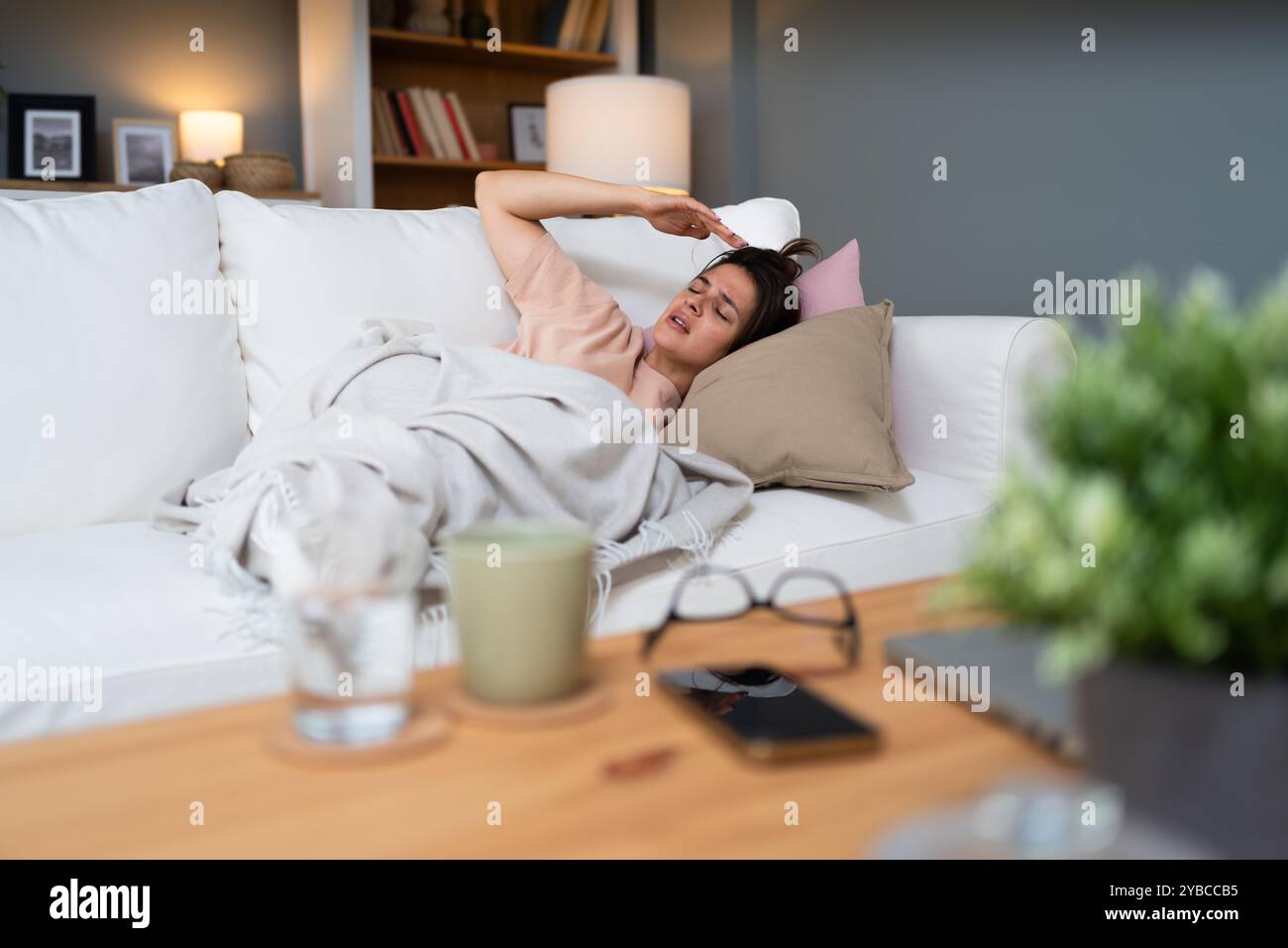 Femme dormant sur le canapé à la maison se reposant enveloppant dans le plaid ressentant de mauvais symptômes. Fille souffrant de grippe saisonnière ou de rhume. Se sentir malsain avec influenz Banque D'Images