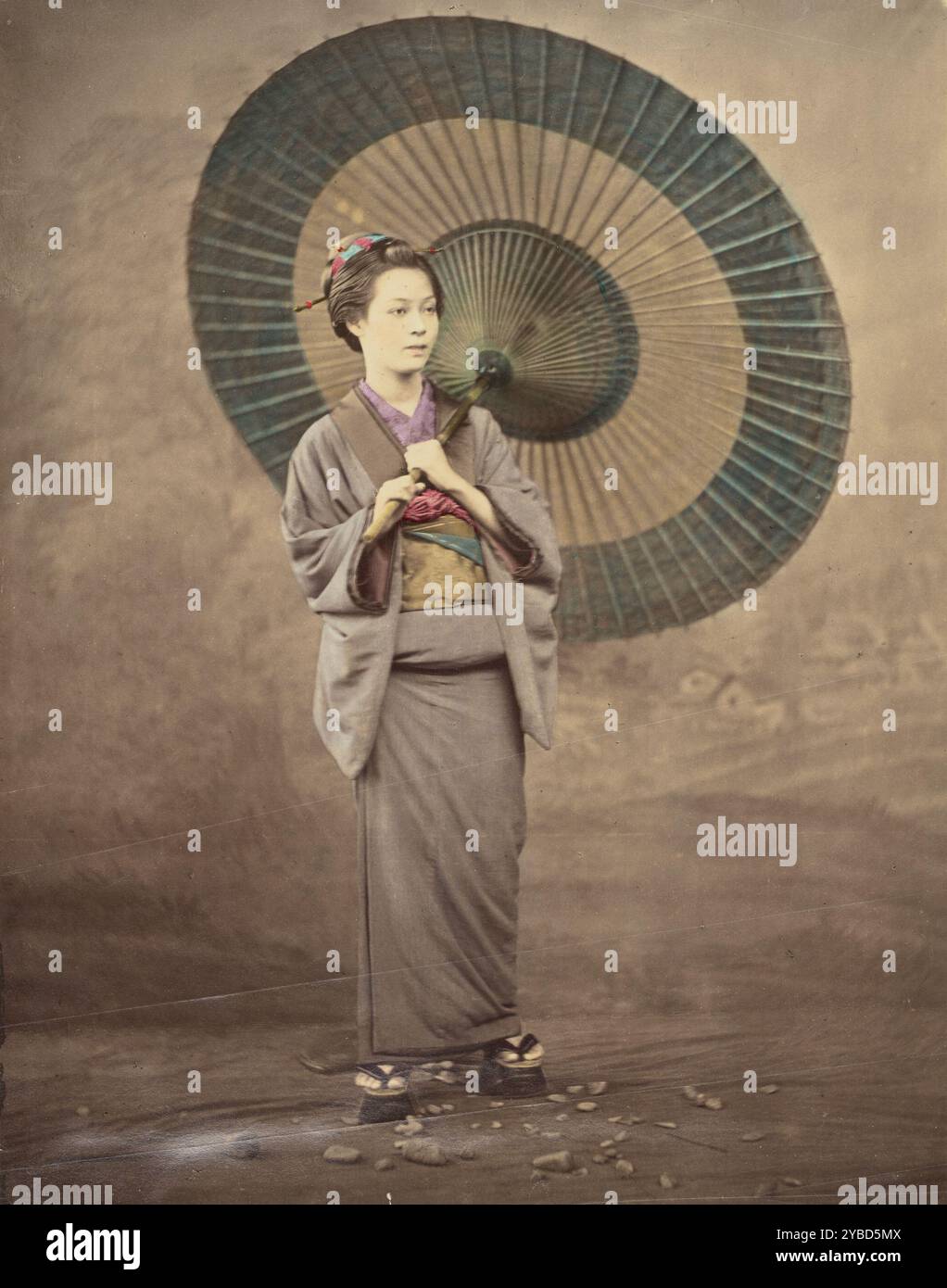 Femme japonaise tenant un grand parasol, 1868-1880. Portrait de studio d'une femme debout avec un parapluie ouvert en papier huile tenu sur son épaule. Banque D'Images