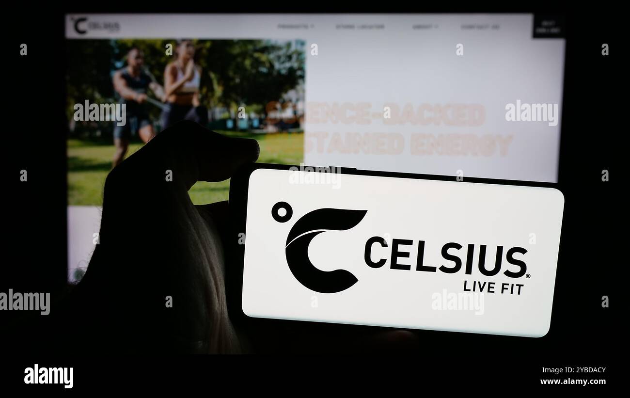Personne tenant un smartphone avec le logo de la société américaine de boissons Celsius Holdings Inc sur l'écran devant le site Web. Concentrez-vous sur l'affichage du téléphone. Banque D'Images