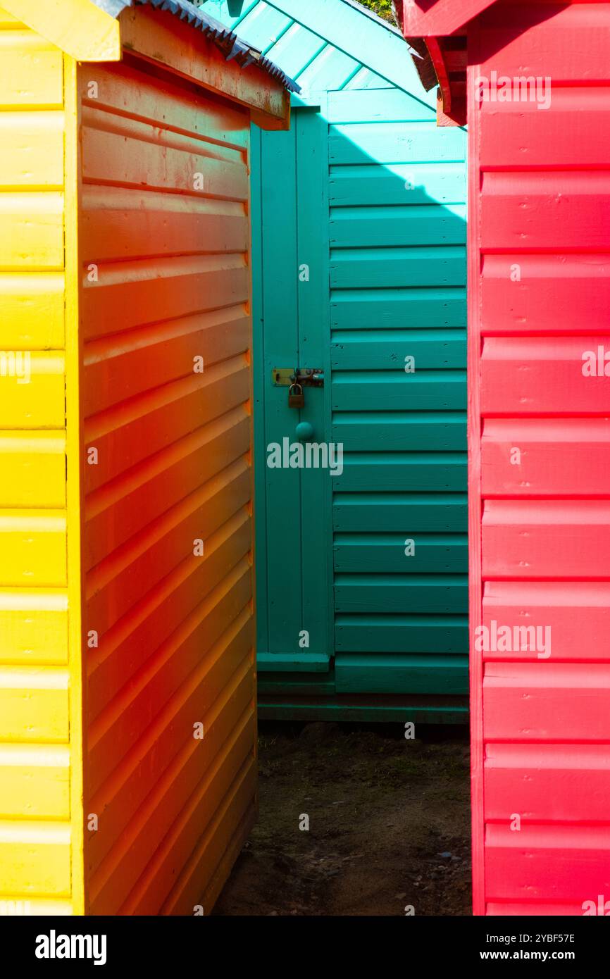 Un gros plan de trois cabanes de plage peintes de couleurs vives, retirées de la plage pour le stockage hivernal Banque D'Images