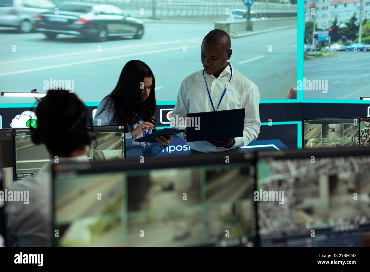 Femme indienne travaillant avec son collègue pour enregistrer un numéro de plaque d'immatriculation, surveillant le trafic par le système radar de surveillance CCTV. Divers employés de l'agence supervisent les séquences vidéo. Banque D'Images