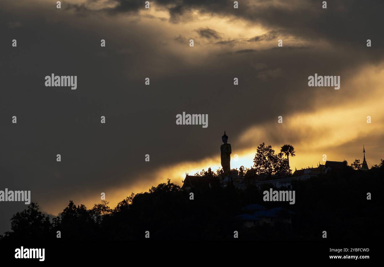 Chiang mai, Thaïlande. 18 octobre 2024. Les derniers rayons du soleil couchant disparaissent lentement au-dessus de l'horizon, avec le grand Bouddha debout en toile de fond à Wat Phra That Doi Kham. Les reflets du ciel au coucher du soleil affichent une variété de couleurs, telles que des teintes dorées et rouges, qui peuvent être vues chaque année en octobre avant l'arrivée de la saison d'hiver en Thaïlande. (Crédit image : © Pongmanat Tasiri/SOPA images via ZUMA Press Wire) USAGE ÉDITORIAL SEULEMENT! Non destiné à UN USAGE commercial ! Banque D'Images
