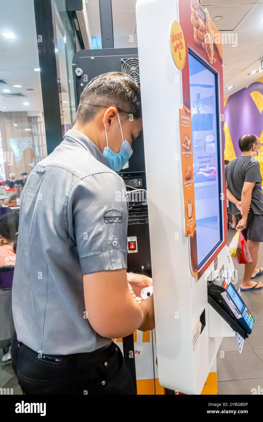Un employé réparant l'écran tactile pour commande à l'arrière, McDonald's Tiong Bahru Singapore Banque D'Images