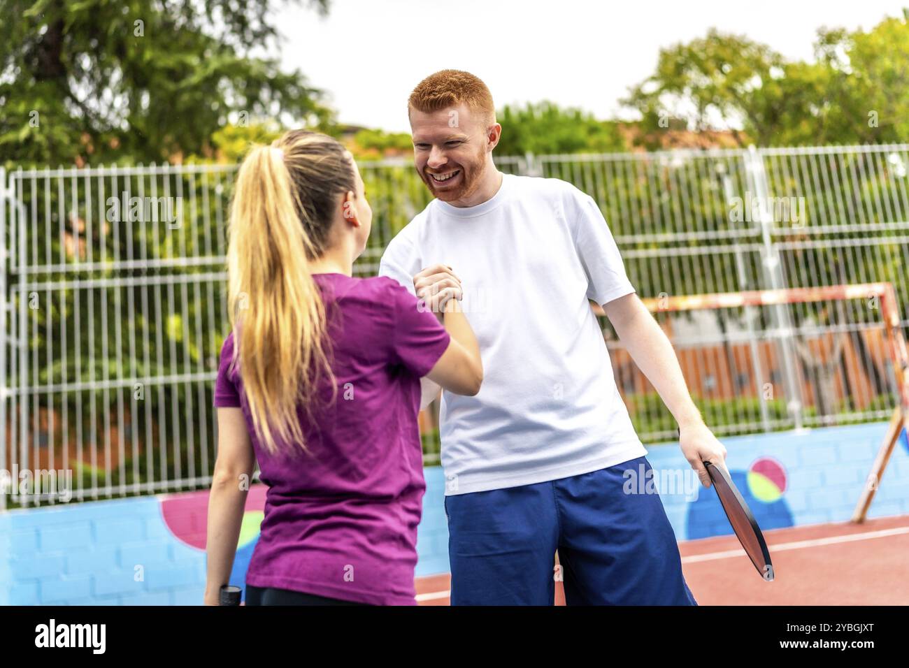 Heureuse équipe caucasienne féminine et masculine de joueurs de pickelball serrant la main après le jeu à la fin d'un match de paire Banque D'Images