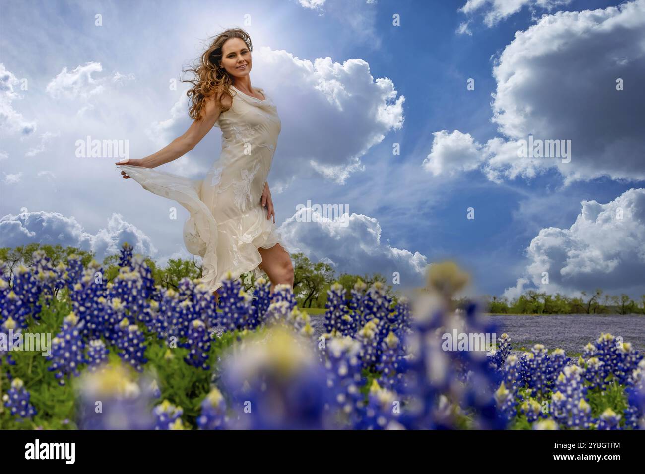 Un beau modèle brune profite d'un champ de fleurs Bluebonnet un jour de printemps Banque D'Images