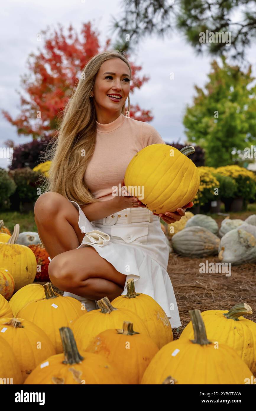 Une belle femme blonde européenne pics quelques citrouilles et fleurs pour les festivals d'automne à venir Banque D'Images