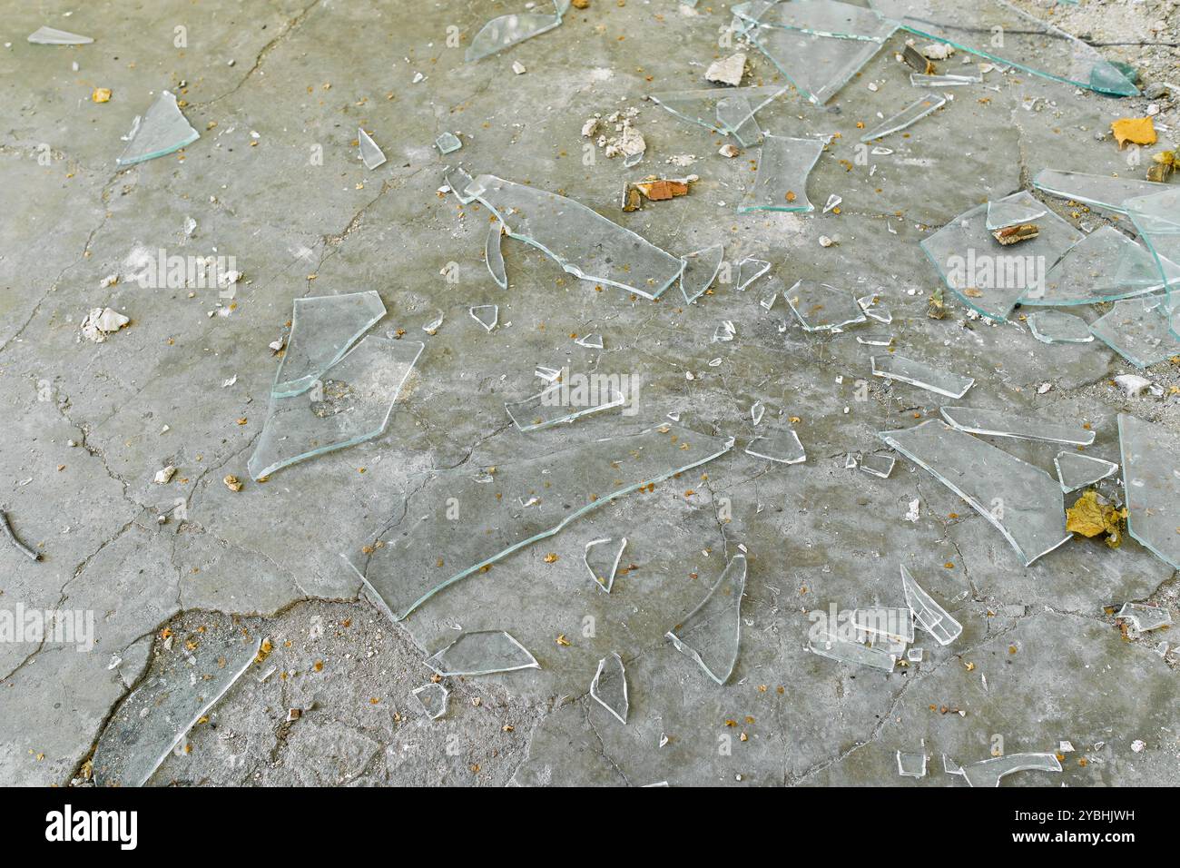 Des morceaux de verre brisé reposent sur la surface de béton. Un grand nombre de éclats de verre transparent reposent sur le sol Banque D'Images