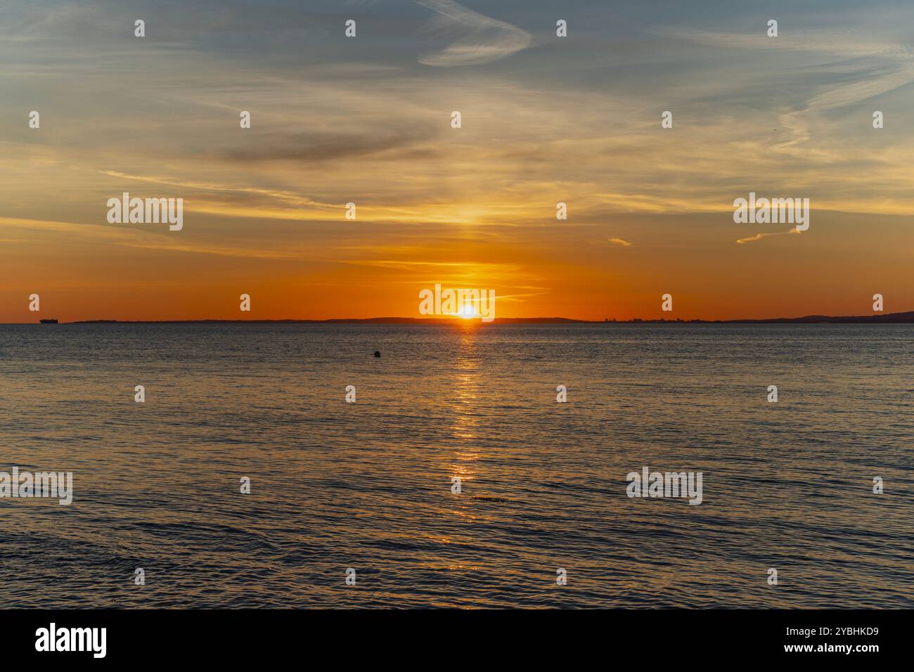 Le soleil sur le point de se coucher sur la côte galloise avec une lueur orangée rougeâtre le long de l'horizon Banque D'Images