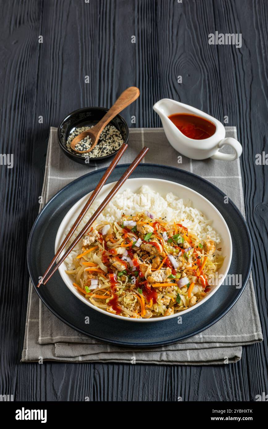 roulé aux œufs de tofu, chou sautés, tofu émietté assaisonné servi dans une sauce sucrée et salée servi sur du riz dans un bol sur une table en bois noir avec des côtelettes Banque D'Images