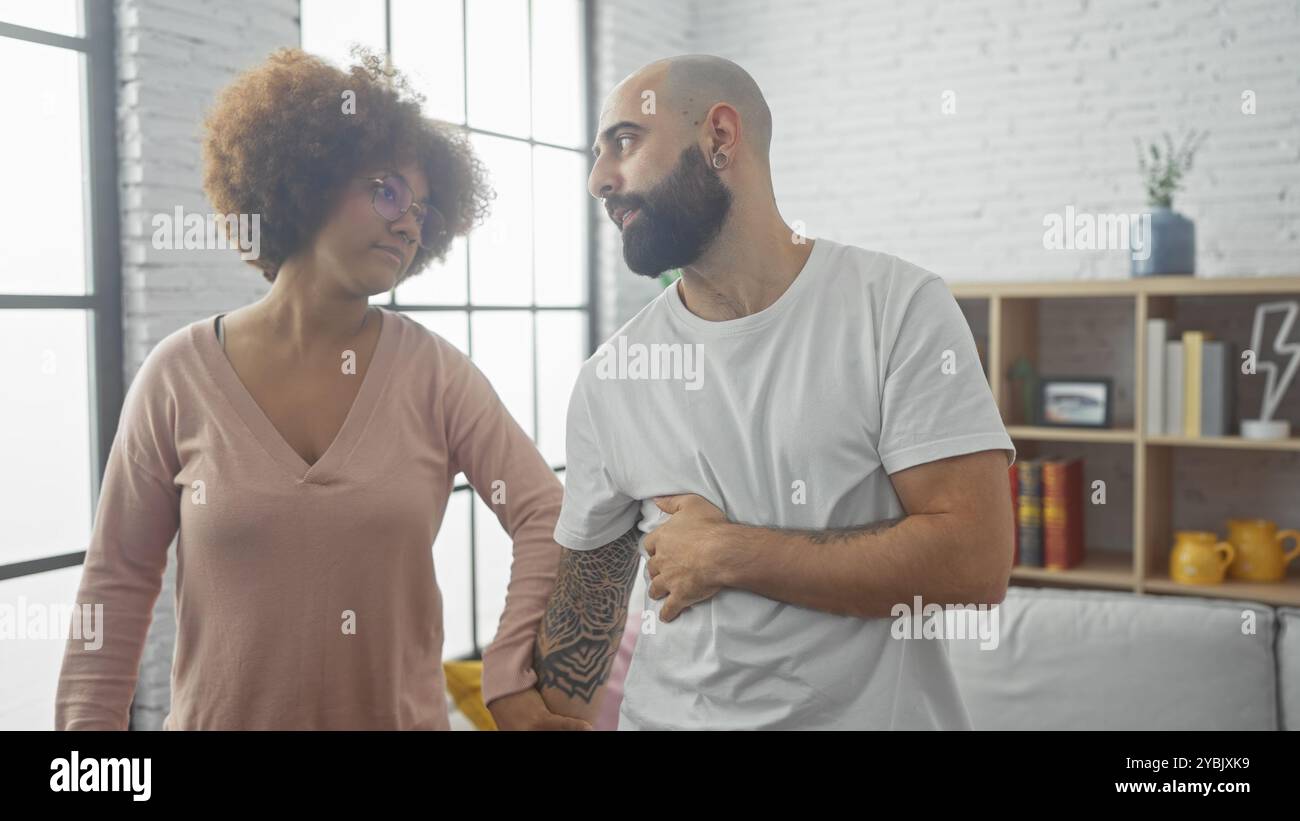 Un homme et une femme dans un salon moderne, enfermant les yeux dans un moment franc et intime, incarnant l'amour urbain et la convivialité. Banque D'Images