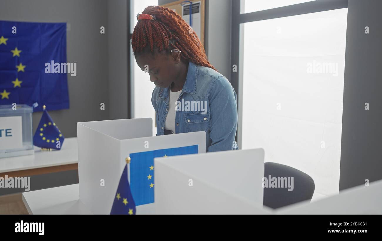 Jeune femme africaine votant dans la salle électorale européenne avec des drapeaux de l'ue Banque D'Images