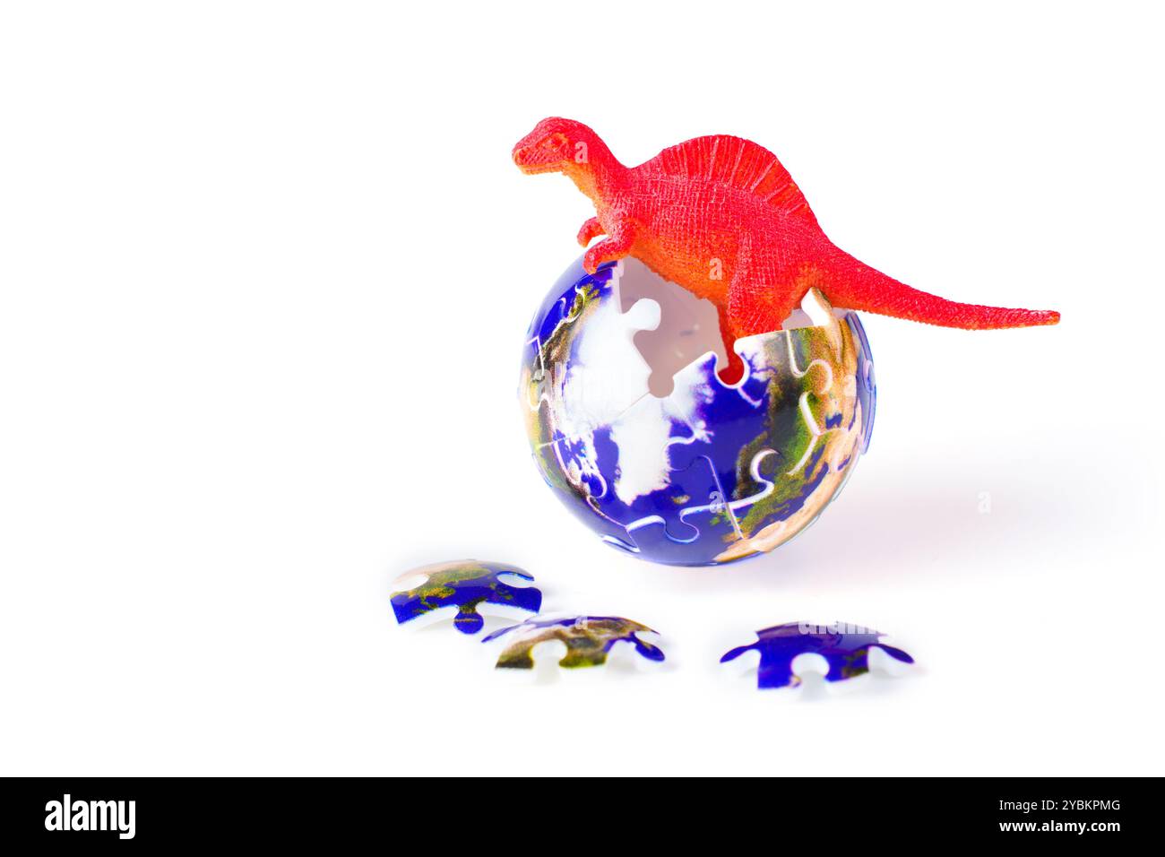 Dinosaure rouge vif debout dans un globe fait de pièces de puzzle avec des pièces supplémentaires dispersées, sur un fond blanc propre, représentant le Banque D'Images