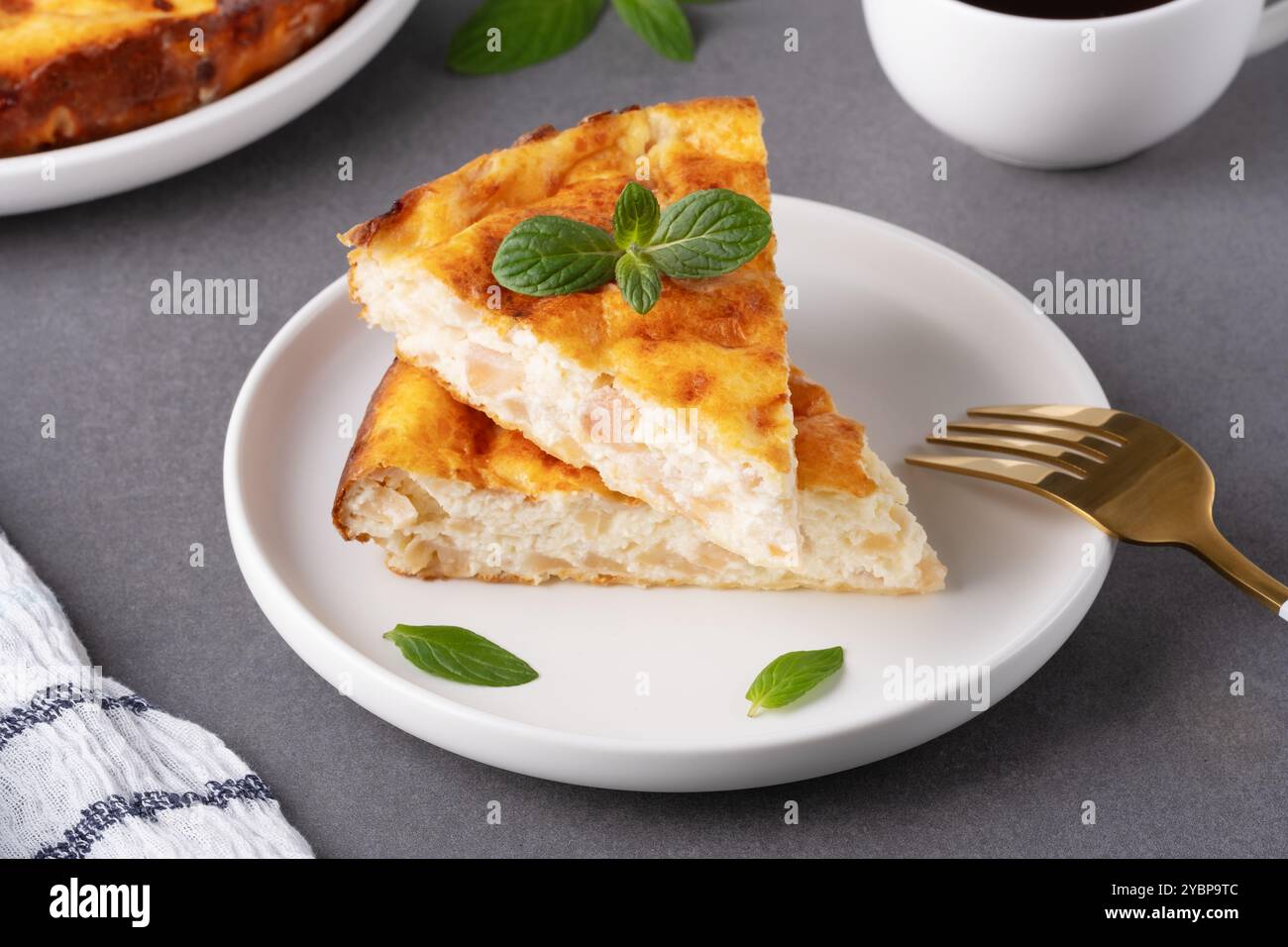 Délicieuse tarte aux pommes maison servie avec du café et garnie de feuilles de menthe sur une table de cuisine confortable Banque D'Images