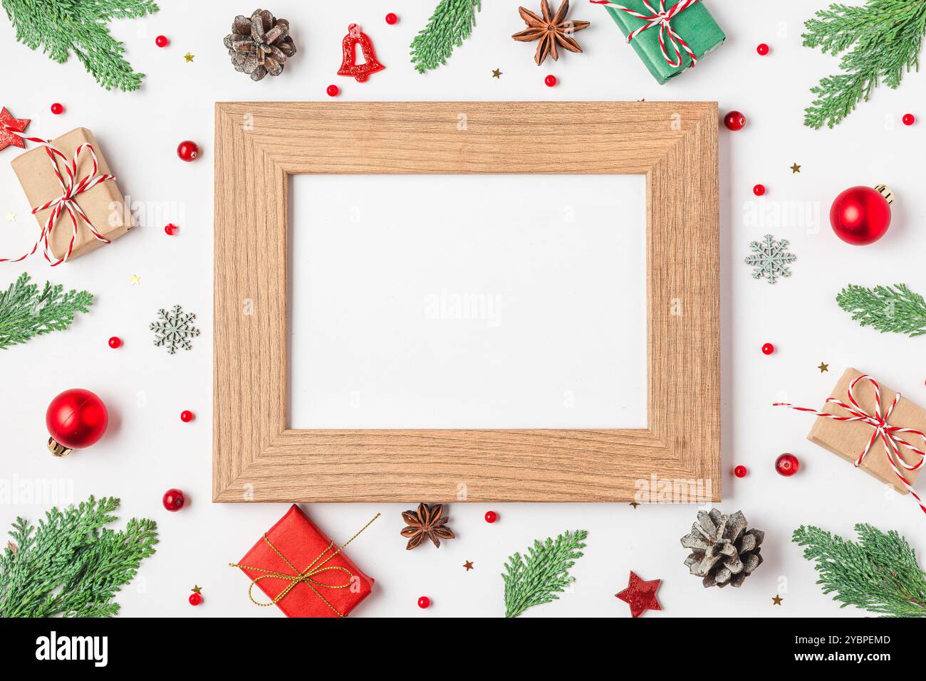 Cadre photo vierge avec décorations de Noël, branches de sapin, boîtes cadeaux, pommes de pin sur fond blanc. Pose à plat. Maquette. Bonne année et bon hiver Banque D'Images