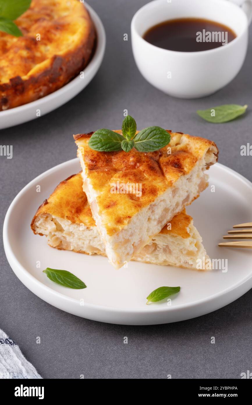 Délicieuse tarte aux pommes maison servie avec du café et garnie de feuilles de menthe sur une table de cuisine confortable Banque D'Images