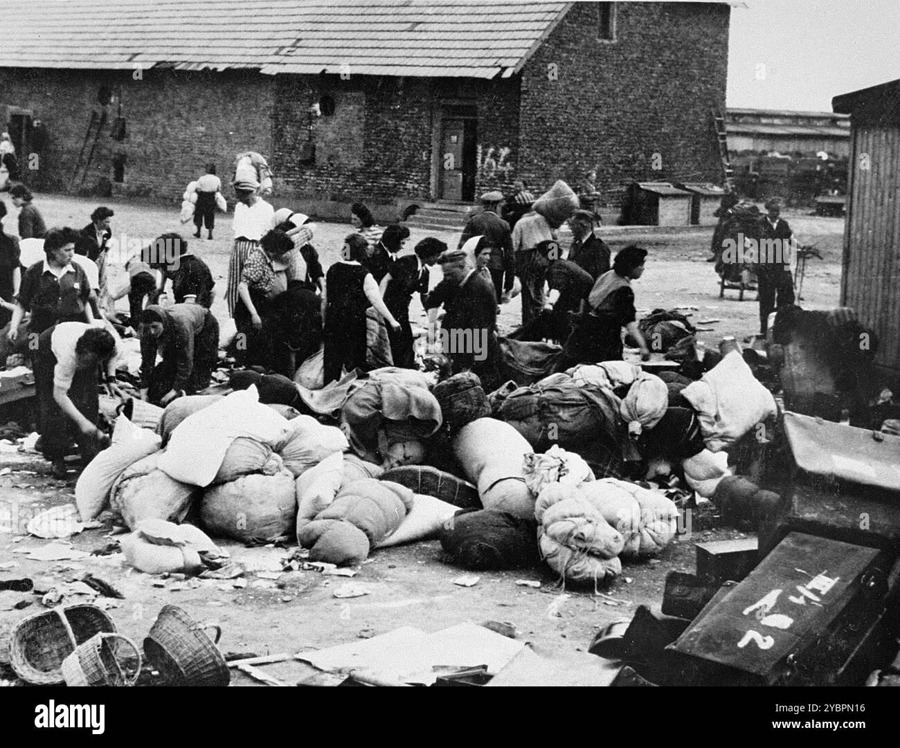 Les prisonniers des Aufräumungskommando (commandos d'ordre) déchargent les biens confisqués d'un transport de Juifs de Hongrie dans un entrepôt à Auschwitz-Birkenau. Les Juifs en Hongrie étaient relativement en sécurité jusqu'à ce qu'Hitler, craignant que la Hongrie cherche un accord avec les alliés, ordonne l'invasion du pays en mars 1944. Entre le 15 mai et le 9 juillet 1944, plus de 434 000 Juifs ont été déportés dans 147 trains, la plupart d'entre eux à Auschwitz, où environ 80% ont été gazés à leur arrivée. La progression rapide des expulsions a été rendue possible par une coopération étroite entre les autorités hongroises et allemandes. Banque D'Images