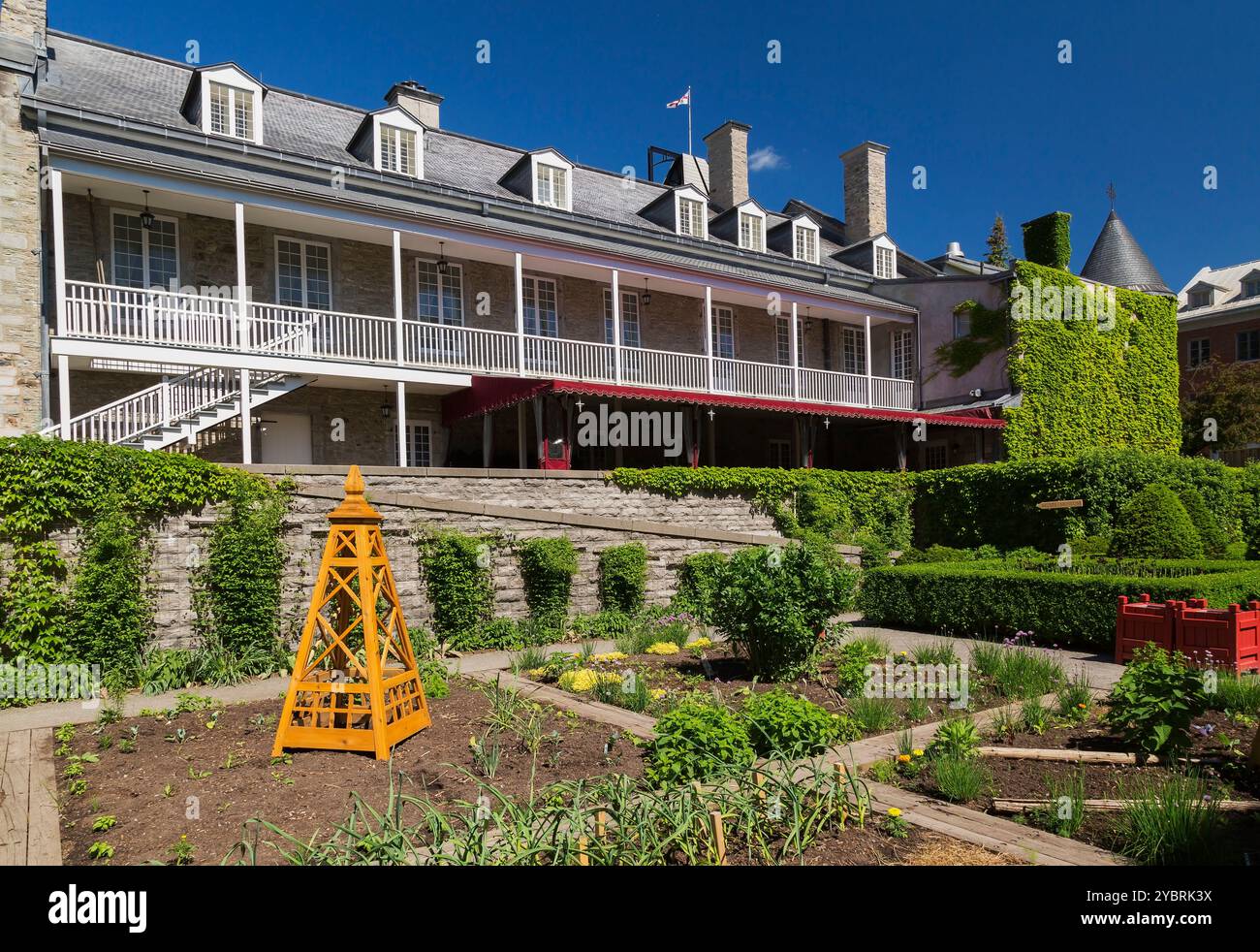 Plantes vivaces dans des parcelles de légumes divisées dans les plantes du gouverneur et le jardin potager derrière Château Ramezay partiellement couvert de vignes grimpantes. Banque D'Images