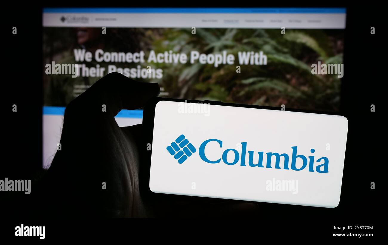 Personne tenant le téléphone portable avec le logo de l'entreprise américaine Columbia Sportswear Company sur l'écran en face de la page Web. Concentrez-vous sur l'affichage du téléphone. Banque D'Images