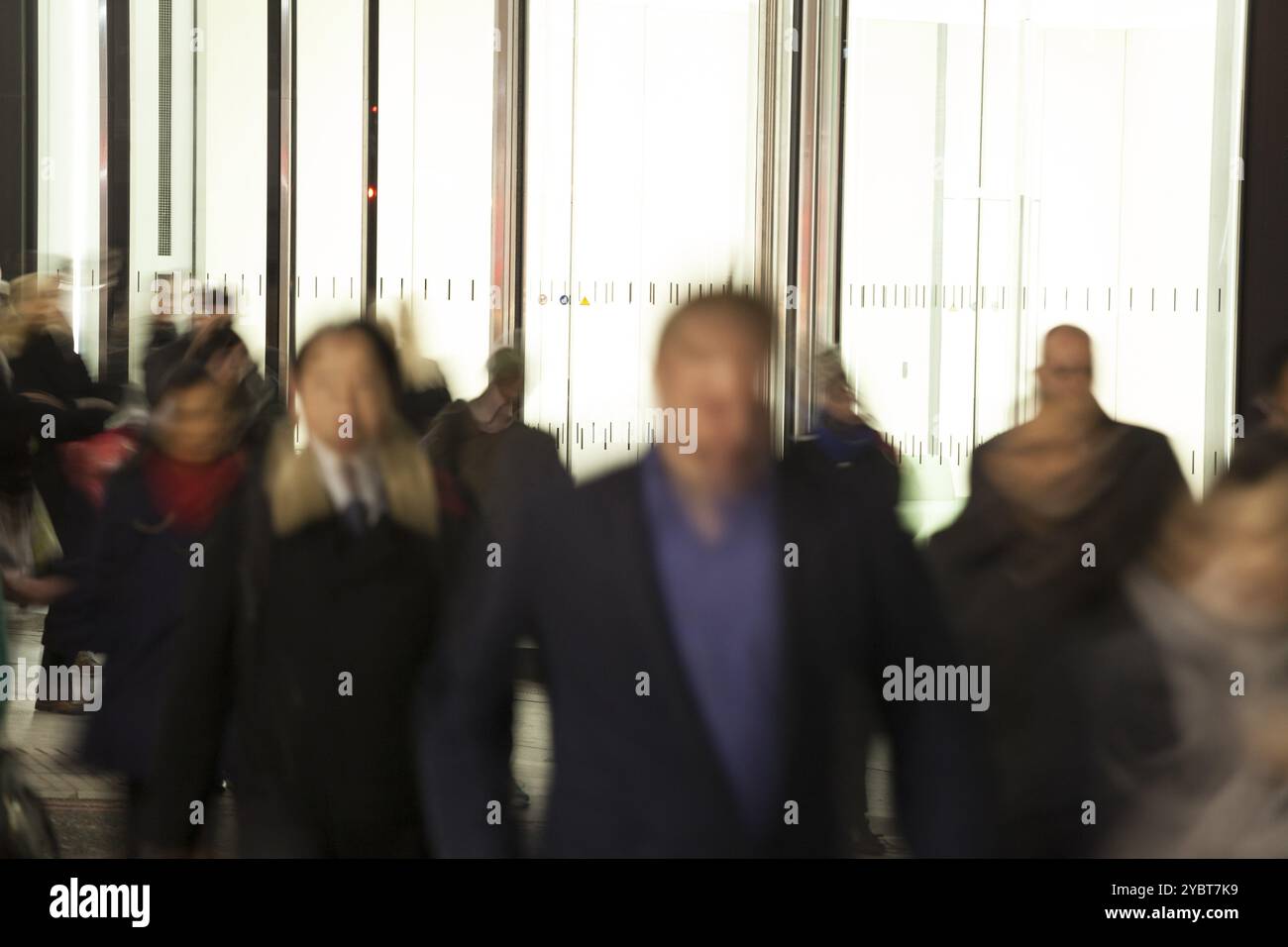 Les personnes qui se déplacent le soir devant un bâtiment lumineux Banque D'Images