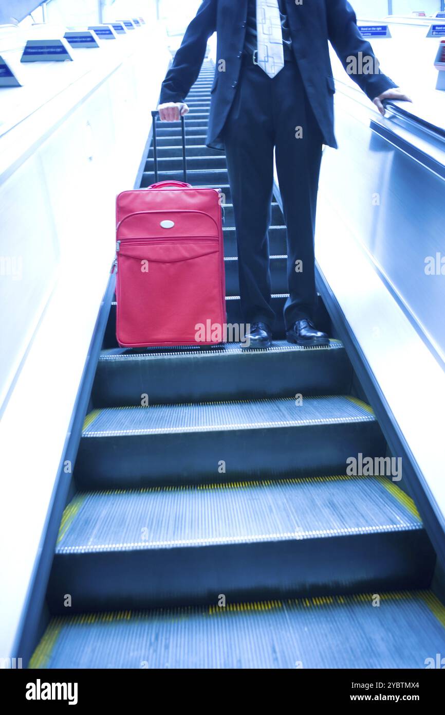 Homme d'affaires qui descend dans un escalator Banque D'Images
