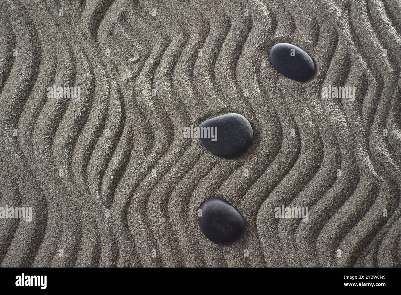 Des dessins sur sable gris clair et les pierres noires dans un petit jardin Zen Banque D'Images