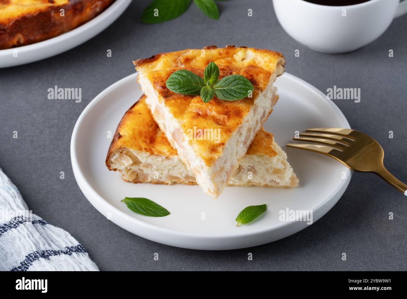 Délicieuse tarte aux pommes maison servie avec du café et garnie de feuilles de menthe sur une table de cuisine confortable Banque D'Images