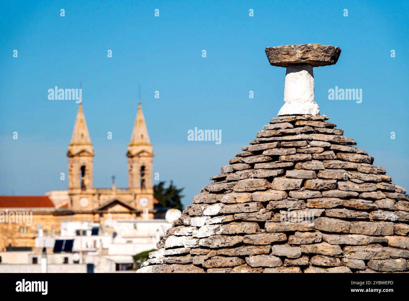 Gros plan du toit en pierre d'un trullo avec la Basilique dei Santi Medici en arrière-plan, Alberobello, Italie. Banque D'Images